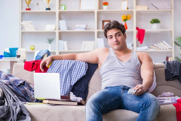 Genç adam dağınık bir odada çalışıyor.