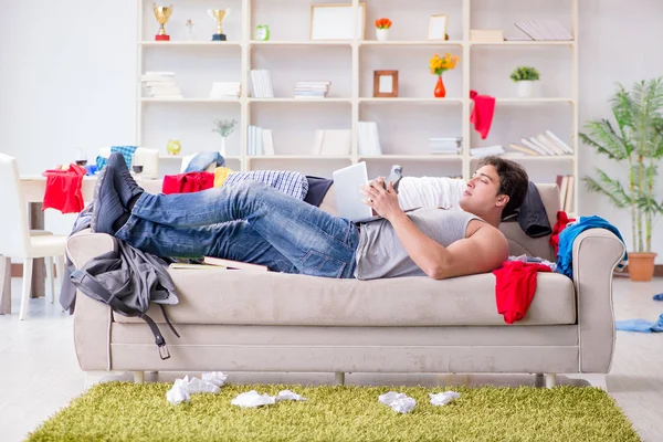 Genç adam dağınık bir odada çalışıyor.