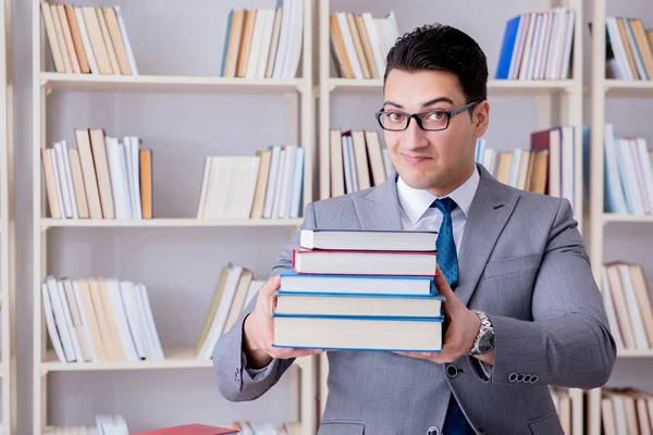 Business law student with pile of books working in library