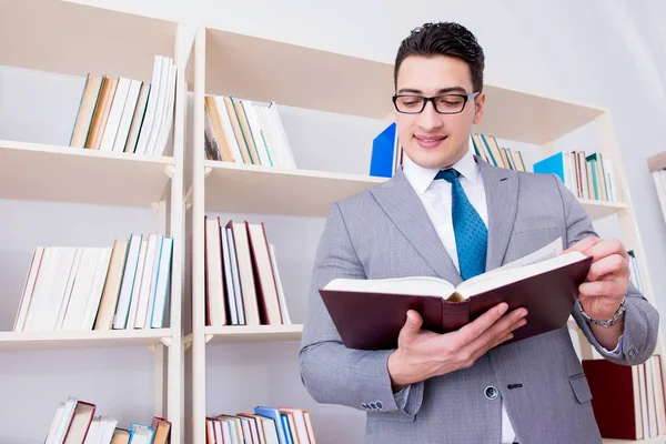 İşadamı öğrenci kütüphanede bir kitap okuyor.