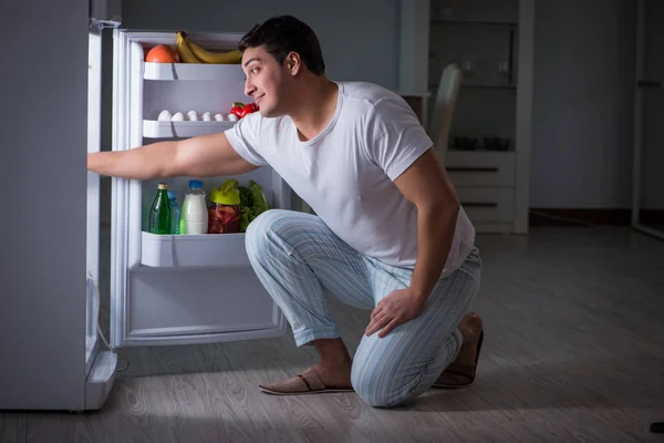 Homem na geladeira comendo à noite — Fotografia de Stock