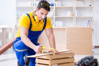 Tamirci marangoz ahşap bir tahtayı kesiyor.