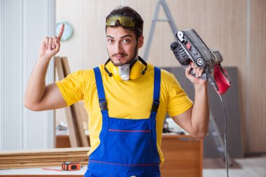 Elektrikli aletlerle çalışan genç marangoz.