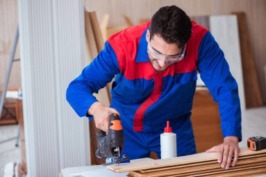 Elektrikli testereyle çalışan genç bir tamirci.