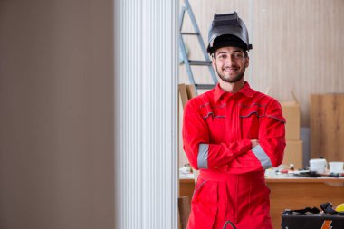 Kaynak tabancası elektrot ve kask takan genç bir tamirci.