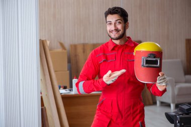 Kaynak tabancası elektrot ve kask takan genç bir tamirci.