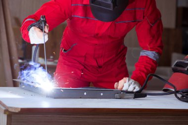 Kaynak tabancası elektrot ve kask takan genç bir tamirci.