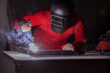 Kaynak tabancası elektrot ve kask takan genç bir tamirci.