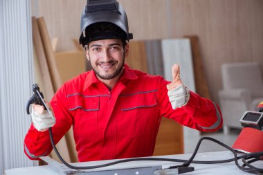 Kaynak tabancası elektrot ve kask takan genç bir tamirci.