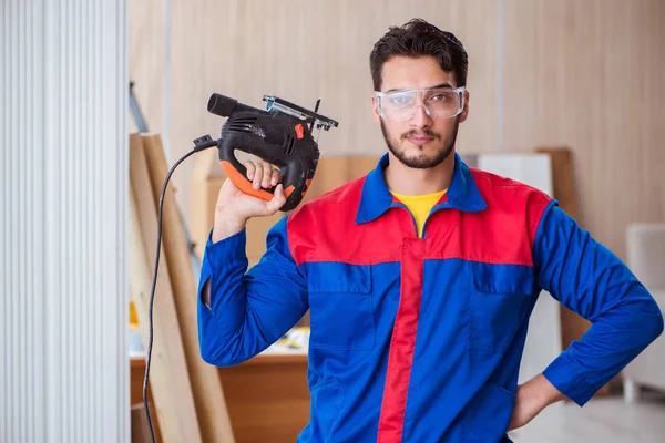 Elektrikli testereyle çalışan genç bir tamirci.