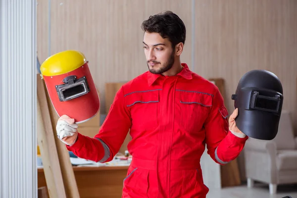 Jovem reparador com um eletrodo de pistola de solda e um soldador de capacete — Fotografia de Stock