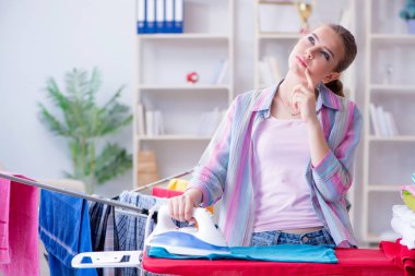 Üzücü kadın evde kıyafetleri ütülüyor.