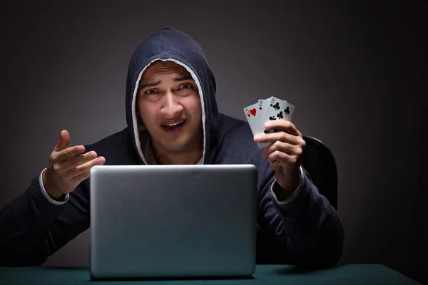 Joven con una sudadera con capucha sentado frente a una computadora portátil — Foto de Stock