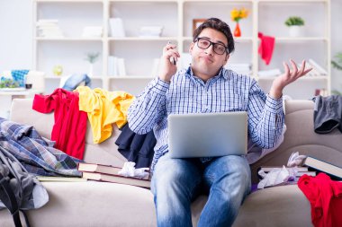 Genç adam dağınık bir odada çalışıyor.