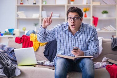 Genç adam dağınık bir odada çalışıyor.