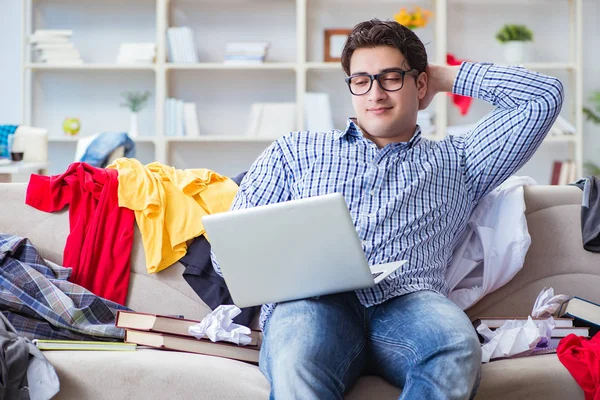 Genç adam dağınık bir odada çalışıyor.