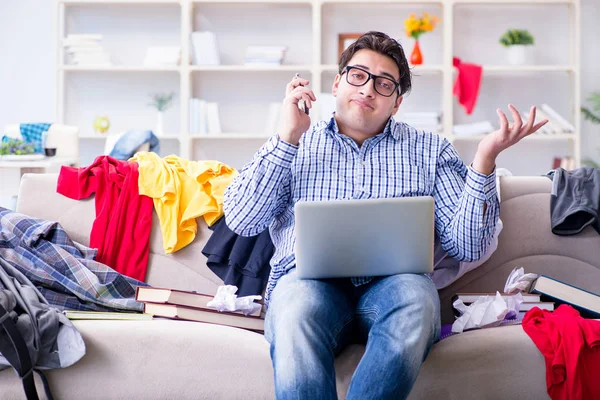 Genç adam dağınık bir odada çalışıyor.