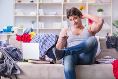 Genç adam dağınık bir odada çalışıyor.