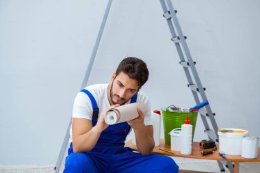 Tamirci, duvar kağıdıyla evde tadilat yapıyor.