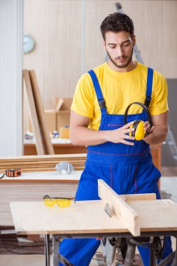 Genç bir marangoz dairesel testereyle odun kesiyor.