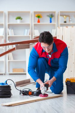 Genç marangoz ahşap kalaslarla çalışıyor.