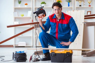 Genç marangoz ahşap kalaslarla çalışıyor.