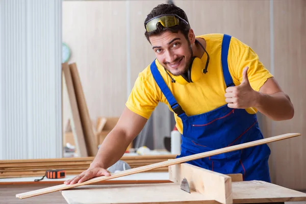 Joven carpintero reparador trabajando cortando madera —  Fotos de Stock