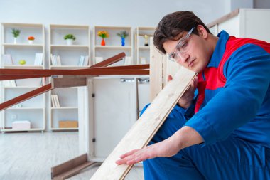 Genç marangoz ahşap kalaslarla çalışıyor.