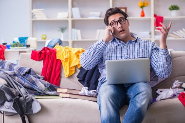 Genç adam dağınık bir odada çalışıyor.