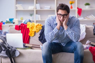 Genç adam dağınık bir odada çalışıyor.