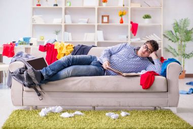 Genç adam dağınık bir odada çalışıyor.