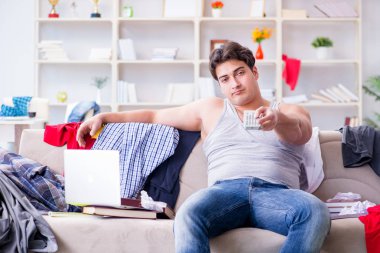 Genç adam dağınık bir odada çalışıyor.