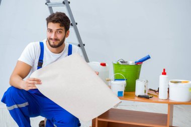 Tamirci, duvar kağıdıyla evde tadilat yapıyor.