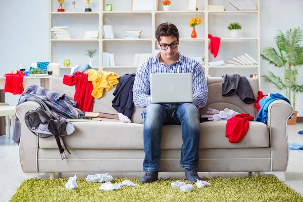 Jeune homme travaillant dans une chambre désordonnée — Photo