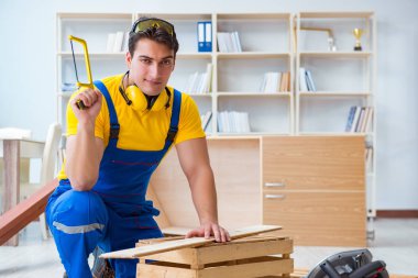 Tamirci marangoz ahşap bir tahtayı kesiyor.