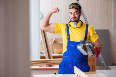 Elektrikli aletlerle çalışan genç marangoz.