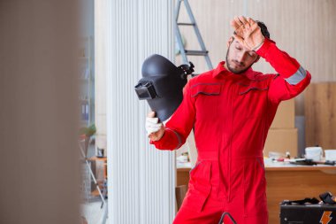 Kaynak tabancası elektrot ve kask takan genç bir tamirci.