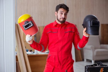 Kaynak tabancası elektrot ve kask takan genç bir tamirci.