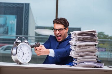 Yığınla evrak işi ve alarm sistemi olan bir iş adamı.