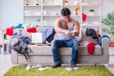 Genç adam dağınık bir odada çalışıyor.