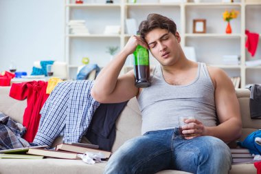 Dağınık bir odada alkol alan genç bir öğrenci.