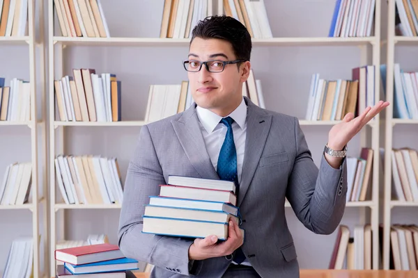 Business law student with pile of books working in library