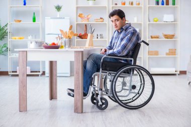 Engelli genç koca mutfakta çalışıyor.