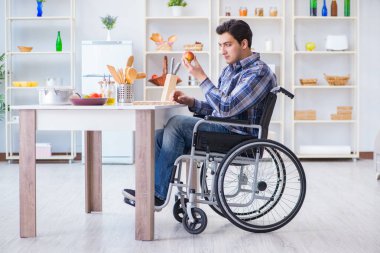 Engelli genç koca mutfakta çalışıyor.