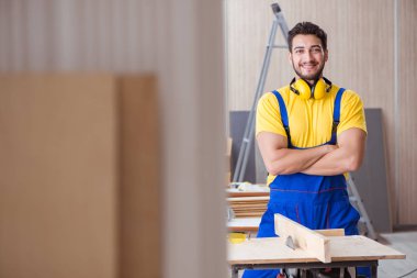 Genç bir marangoz dairesel testereyle odun kesiyor.