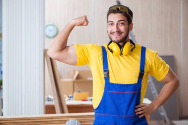 Genç tamirci marangoz odun kesiyor.