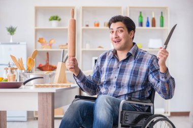 Engelli genç koca mutfakta çalışıyor.