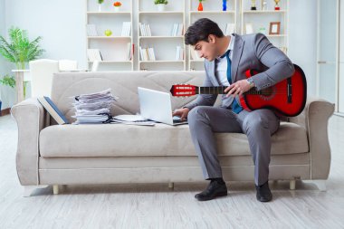 Evde gitar çalan bir iş adamı.