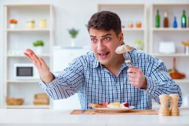 Yemek için evde tatsız yemekler yiyen bir adam.