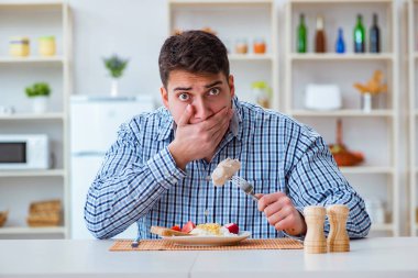 Yemek için evde tatsız yemekler yiyen bir adam.